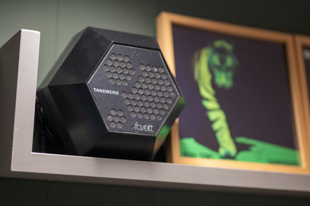 Black geometric speaker on a shelf with artwork