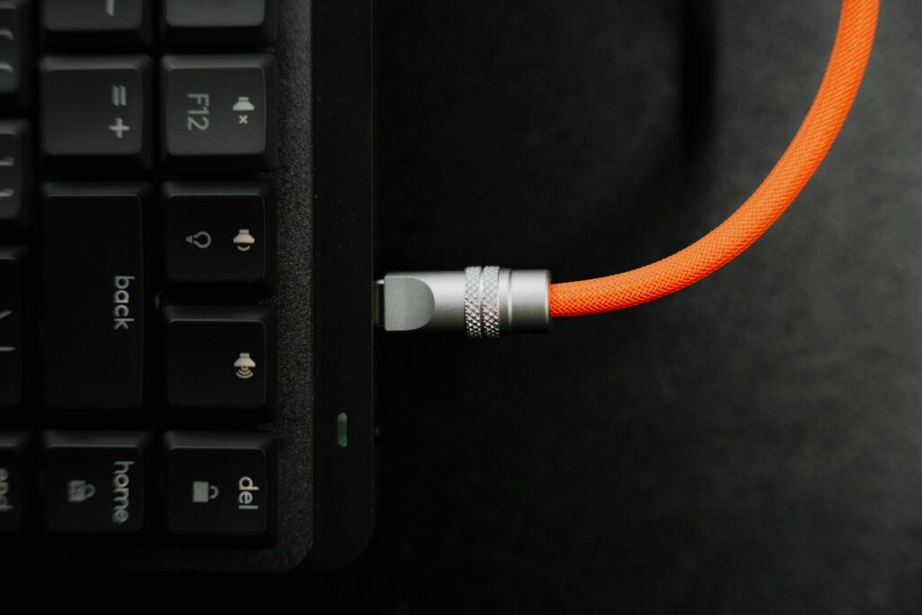 A close up of a computer keyboard with an orange cord