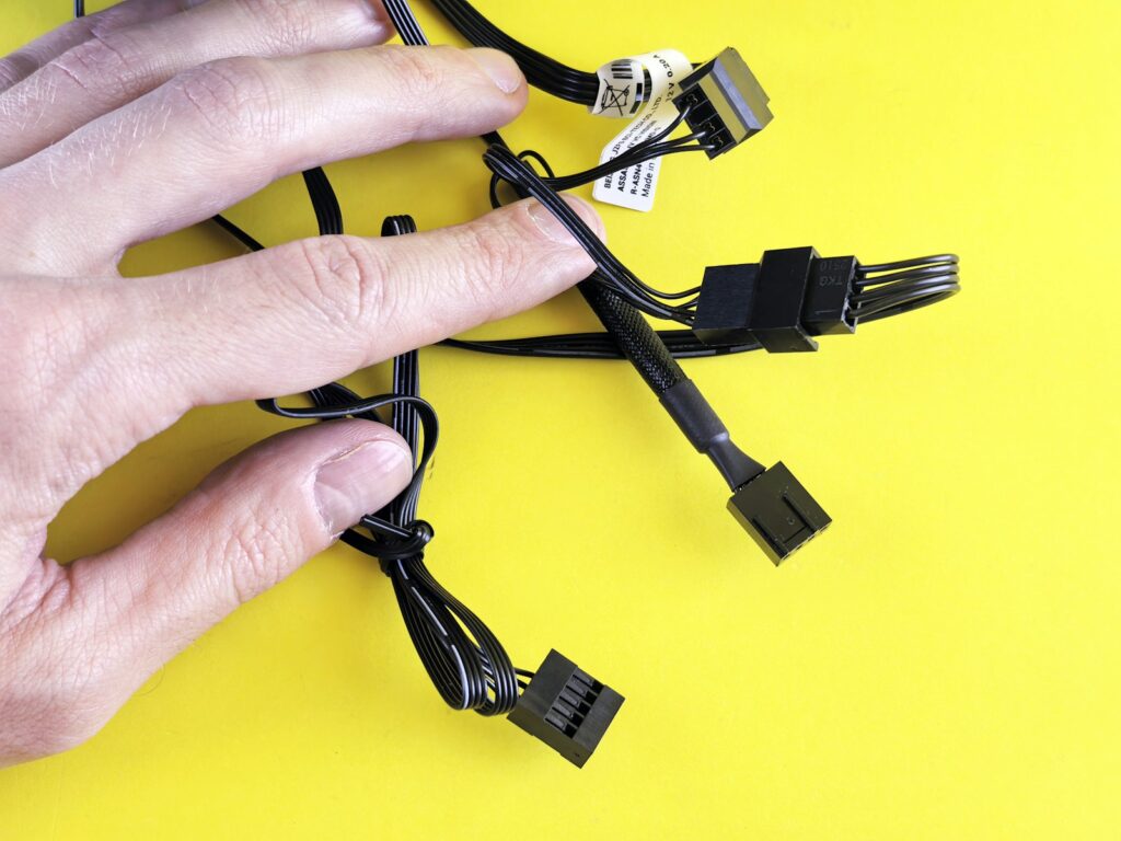 A hand touches computer cables on a yellow background