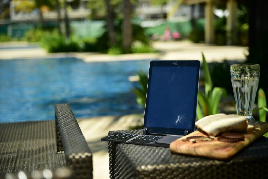 a laptop computer sitting on top of a table next to a pool