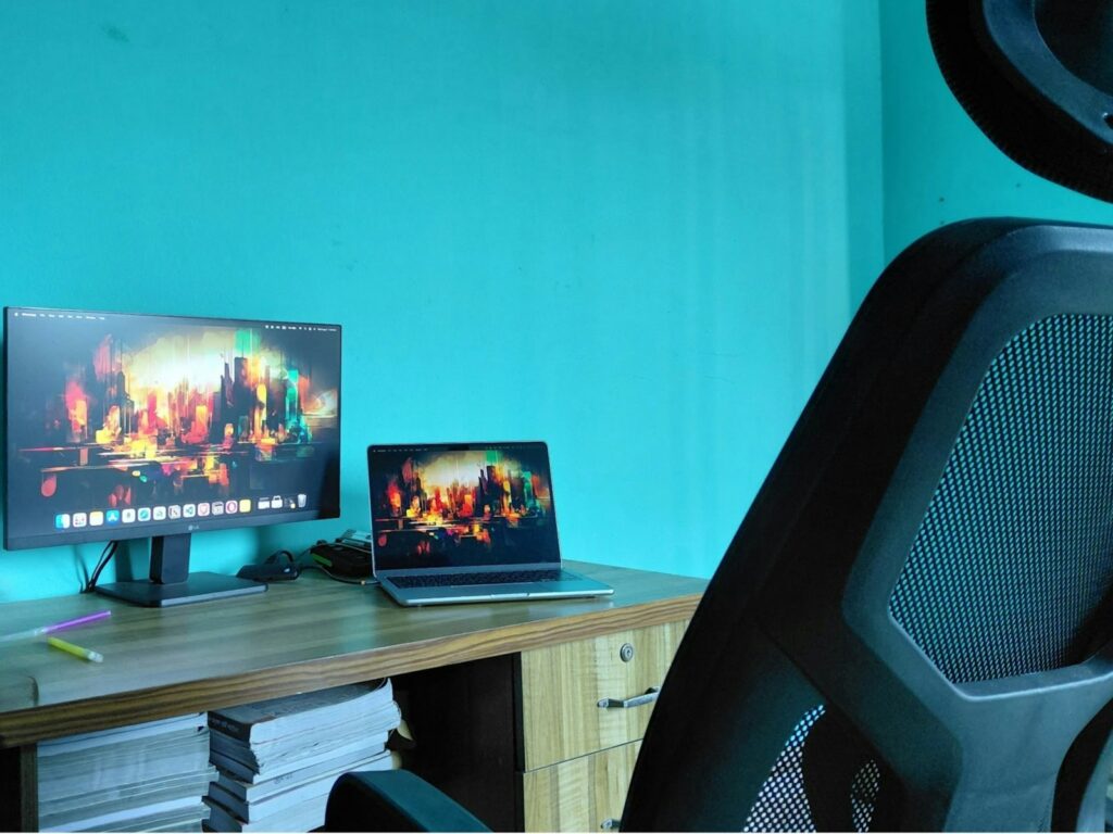 Desk with laptop and monitor displaying cityscapes.